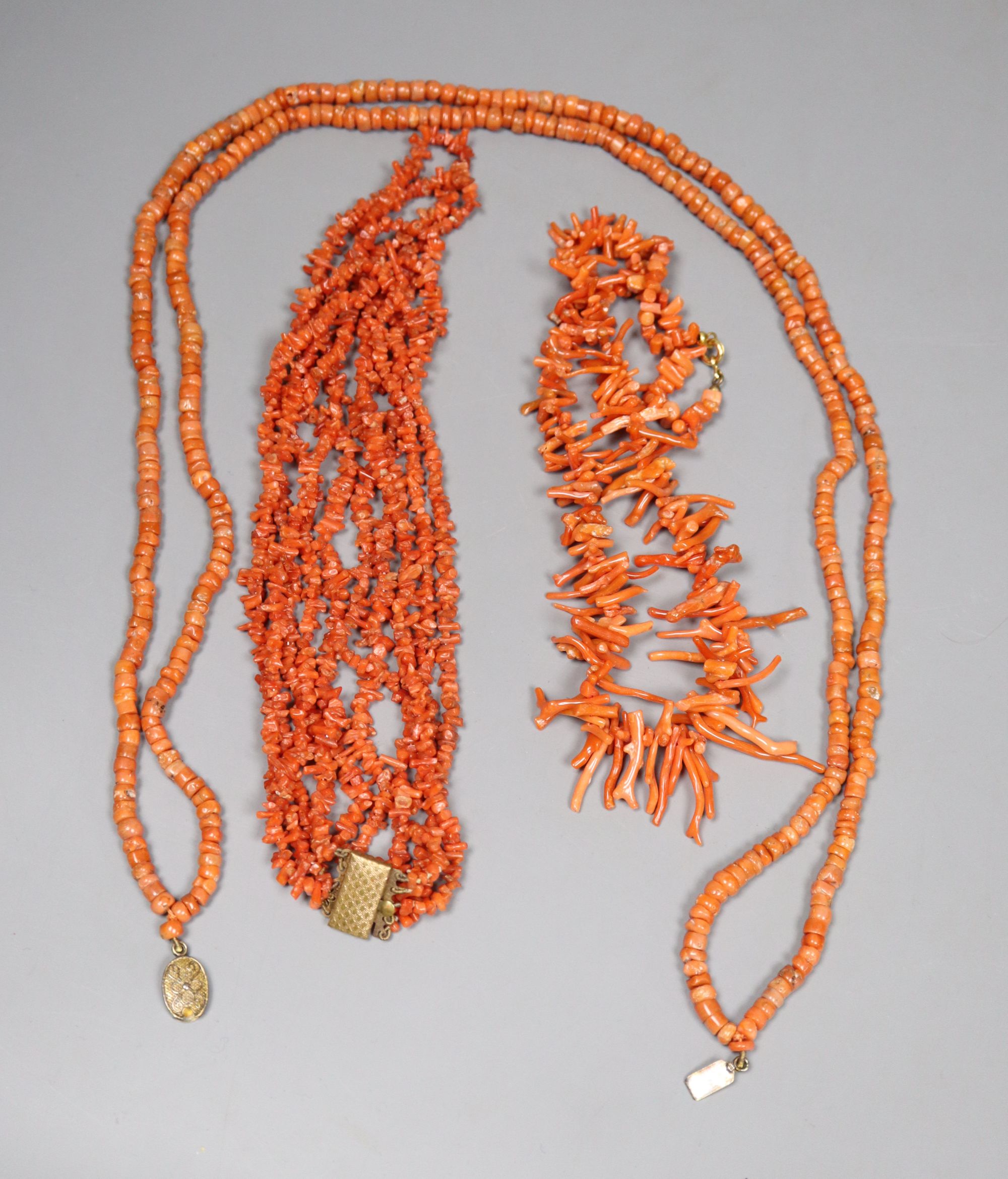 Three assorted coral necklaces including bead and fragment, with gilt metal clasps, longest 62cm, gross weight 153 grams.